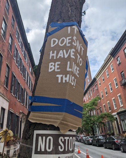 A cardboard sign taped to a telephone pole near the site where a vehicle took the life of Children's Hospital of Philadelphia Dr. Barbara Friedes, while biking home from work on Spruce Street, reads "IT DOESN'T HAVE TO BE LIKE THIS!"