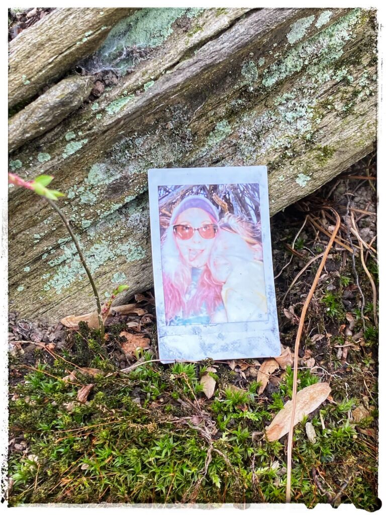 A Polaroid of two friends leans against a log in the Wissahickon forest