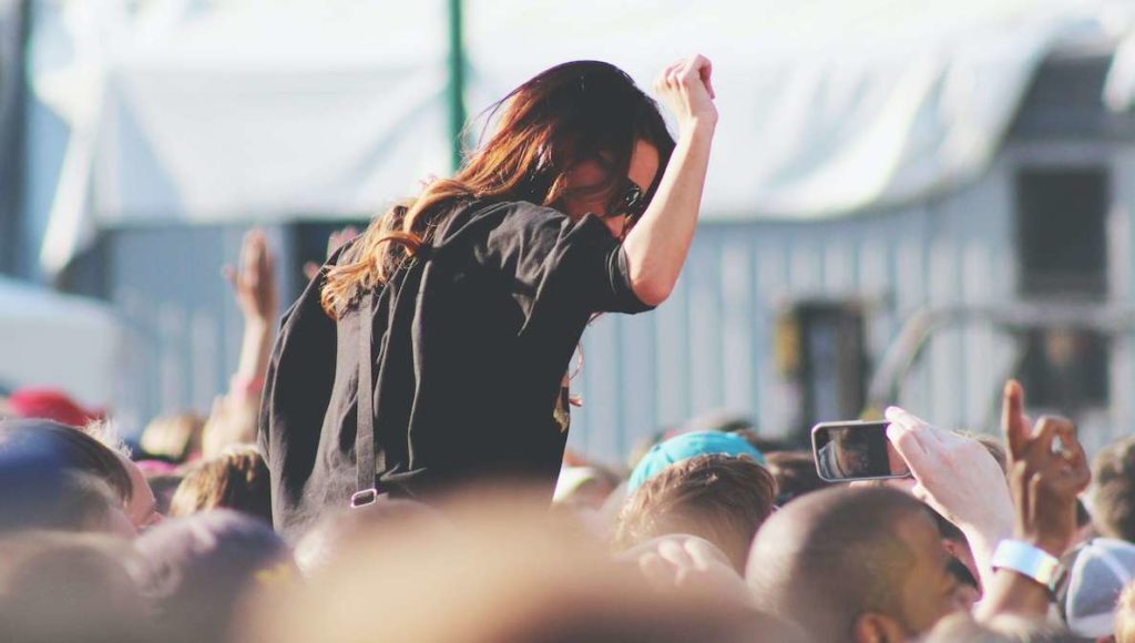 A girl sits on someone's shoulders and raises her arms in glee at the Made in America music festival in Philadelphia