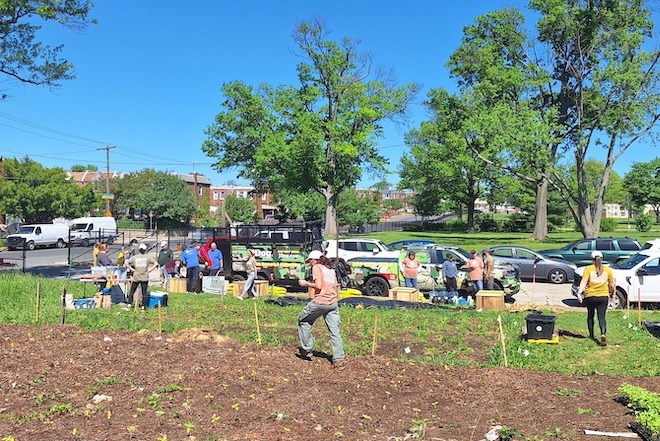 People stand along a sidewalk and in a plot of soil, readying to plant the Heroic Gardens in Northeast Philadelphia.