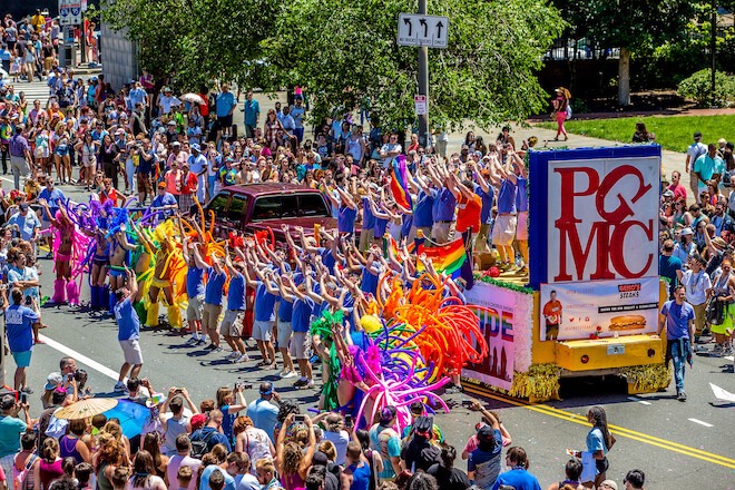 A float bearing the letters PGMC, displayed like Robert Indiana's LOVE sculpture travels along Market Street near Independence Mall in Philadelphia. This is the Philadelphia Gay Men's Chorus and the city's annual Pride Parade.