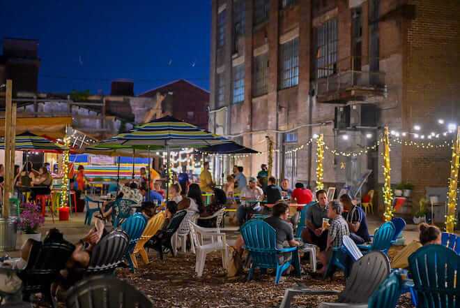 People sit in Adirondack chairs at night behind Attic Brewing Co. in Garmantown, Philadelphia.