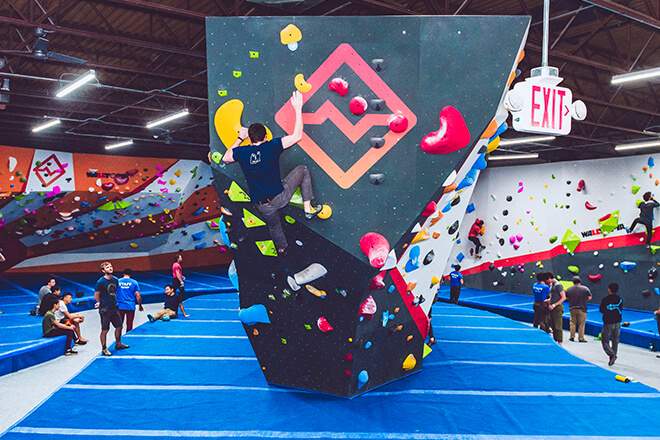 A man climbs a freestanding climbing wall as other people watch at the Cliffs Callowhill, a climbing gym in Philadelphia.