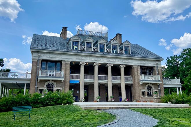 A columned building stands at the end of a walkway. This is Smith Memorial Playhouse, part of Smith Memorial Playground in Philadelphia.