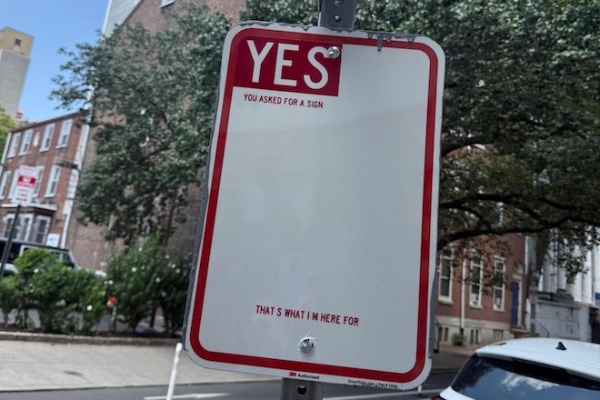 A faux parking sign says "YES" and "You asked for a sign. That's what I'm here for."