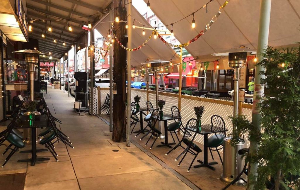 The outdoor dining area at Italian Market Mexican restaurant Blue Corn, decorated with hanging lights and heat lamps