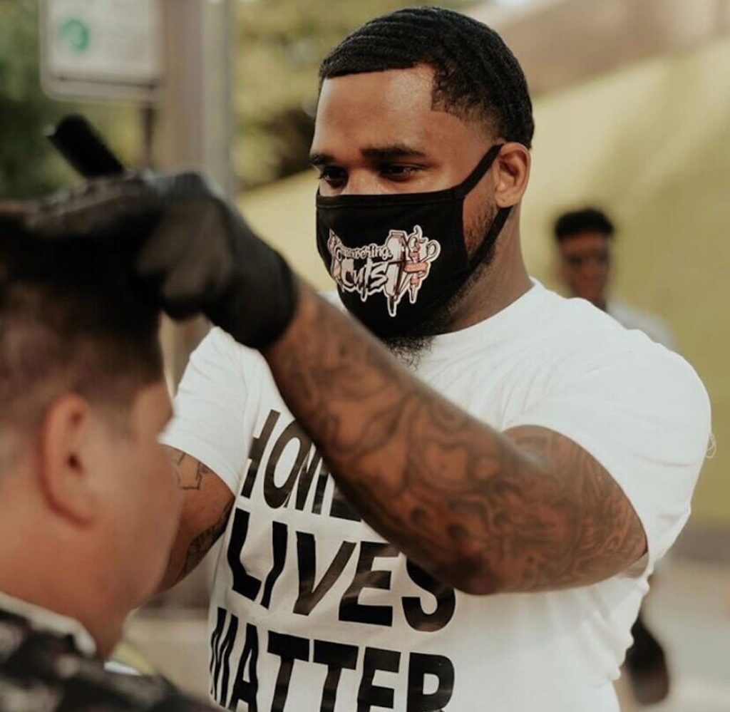 Joshua Santiago of Empowering Cuts gives a haircut to a man experiencing homelessness