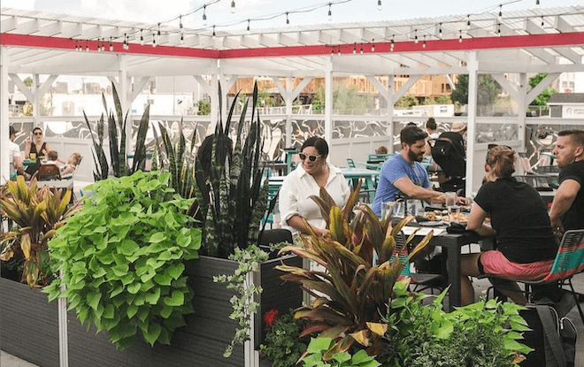 People sit behind planters on the patio of Sor Ynéz, a Mexican restaurant in Kensington, Philadelphia. 