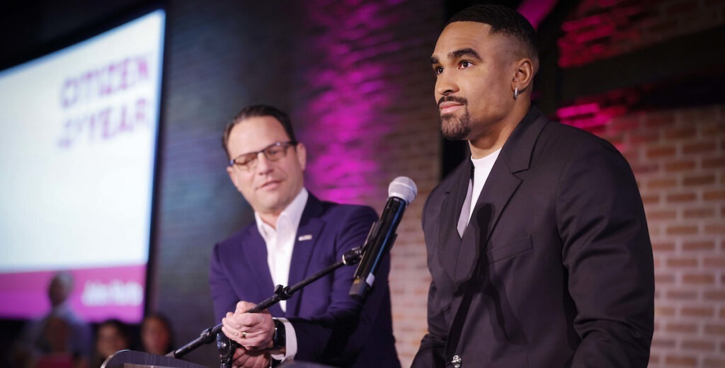 Pennsylvania Governor Josh Shapiro adjusts the mic for Eagles Quarterback and Citizen of the Year Jalen Hurts at the Citizen of the Year Awards.