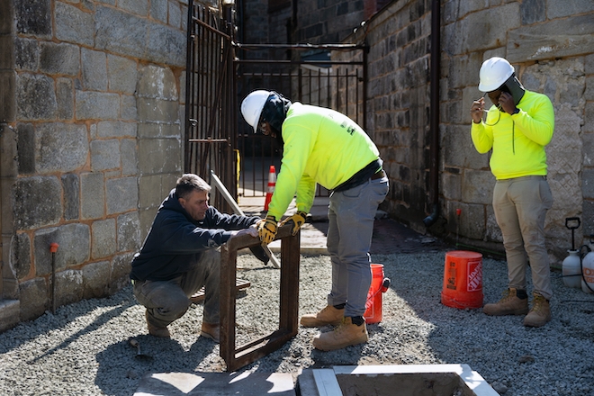 Cement masonry and plastering academy professor Anthony Ditri (left) instructs students Nijir Cornelisu (center) and Carl Moisette on how to fix a sewer.