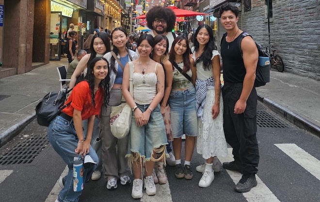 Nine high school and college-age students, many Asian, all dressed on trend, pose on a Manhattan street during a Ginger Arts Center staff trip to Manhattan Chinatown, timed with a meeting with Youth Against Displacement.
