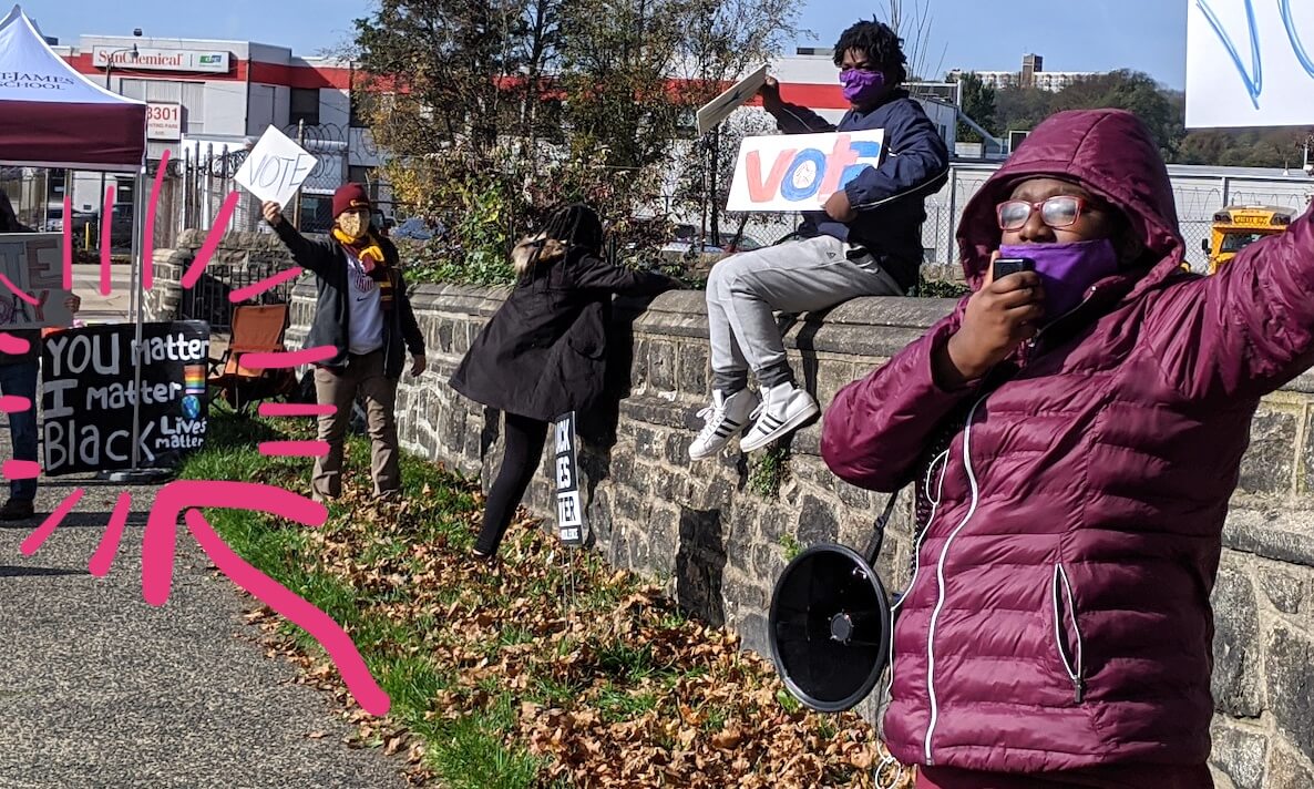 Young people in Philadelphia stand on a highway with signs encouraging people to vote