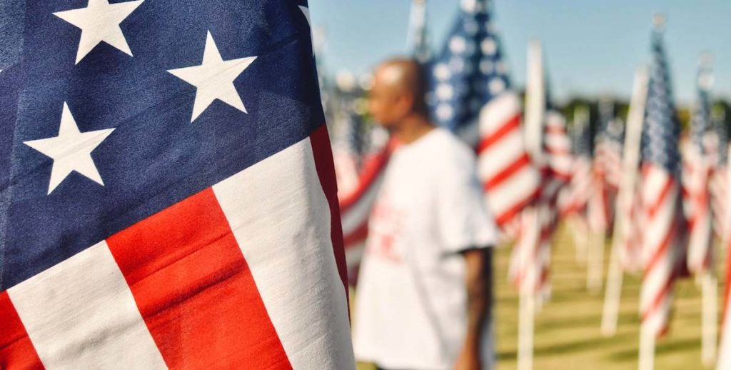 This photo of a veteran wandering through a field of American flags accompanies a roundup about how to help veterans in the United States