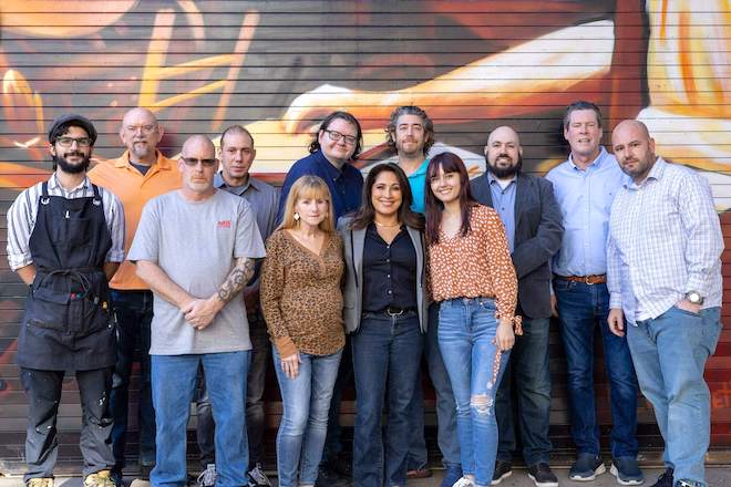 A group of veterans stand together in front of a painted wall.
