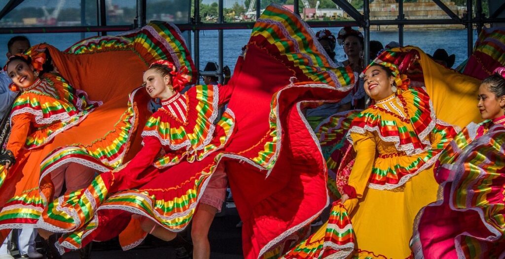Women in bright ruffled dresses dance onstage at the Mexican Independence Day Festival at Penn's Landing.