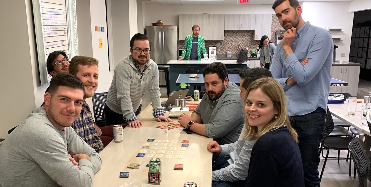 Promptworks employees sit around a table smiling at the camera.