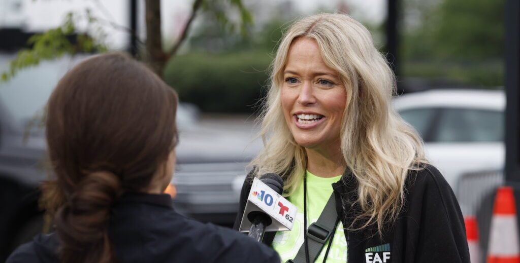 Ryan Hammond, a White woman with long, wavy blonde hair speaks into a news microphone during the Eagles Autism Challenge at Lincoln Financial Field in Philadelphia.