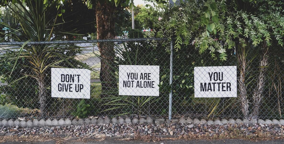 Signs about mental health line a fence.