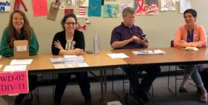 Four poll workers hold up an information table at a polling station in Philadelphia