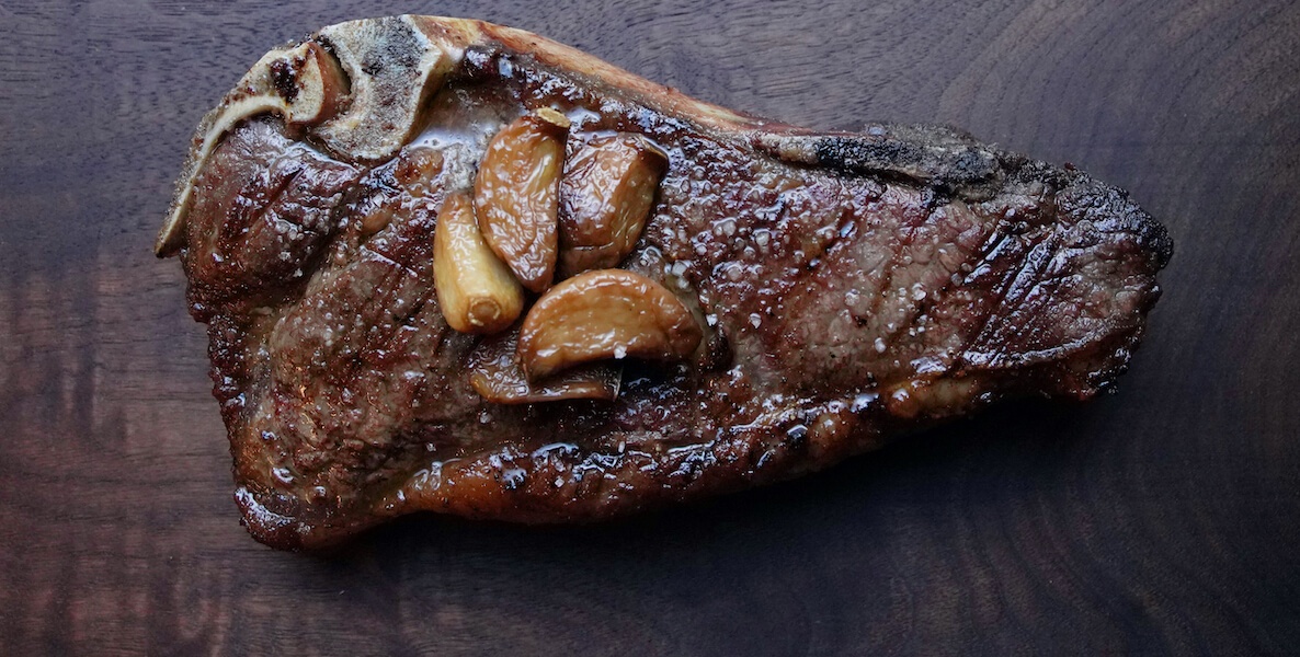 A New York strip steak with roasted garlic on top at Alpen Rose steakhouse in Philadelphia