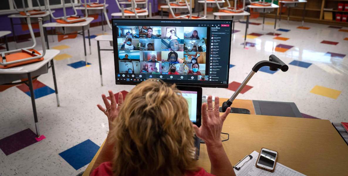 A teacher waves to students over a Zoom class