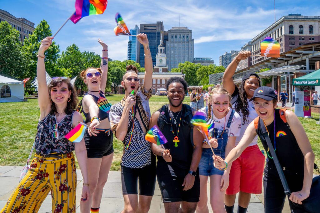 Pride revelers wave rainbow flags in front of Constitution Hall in Philadelphia