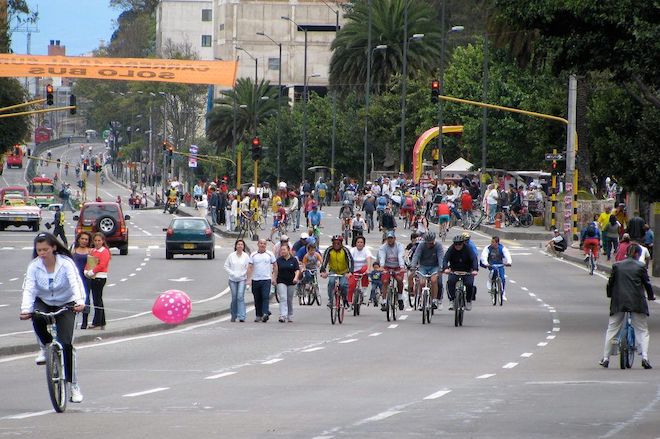 People in Bogota, Colombia ride bicycles and walk along a wide and curved street during a regular car-less open streets event there.