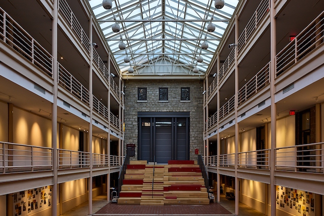 Hamilton Hall's atrium, site of the Celebration of Life for UArts, has a vaulted skylight, septs leading to a belgian blocked wall and door and three floors of open corridors on either side.