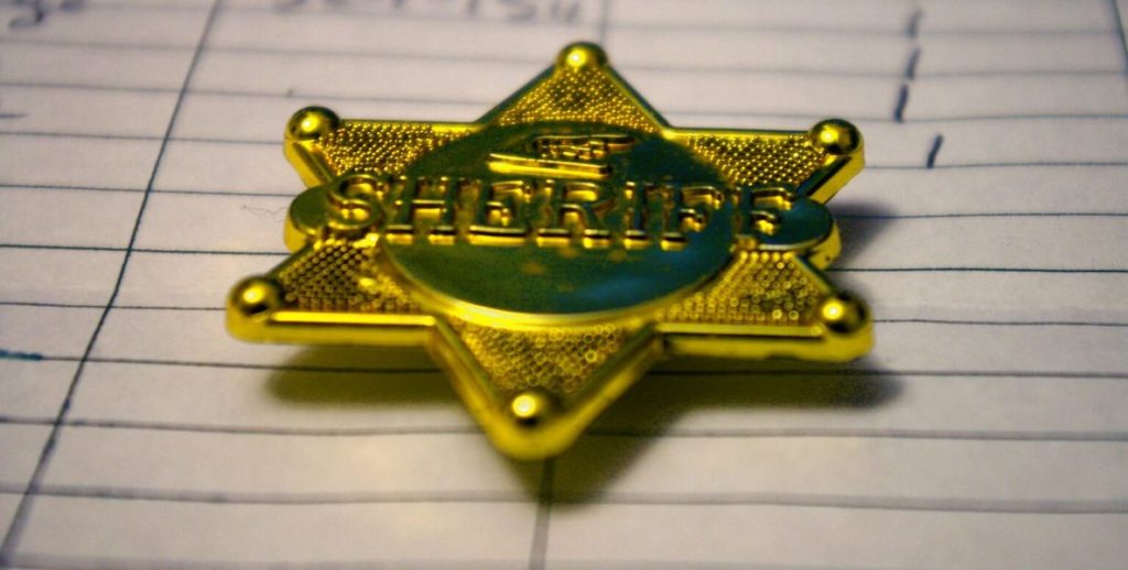 A sheriff's badge lays on a piece of paper.