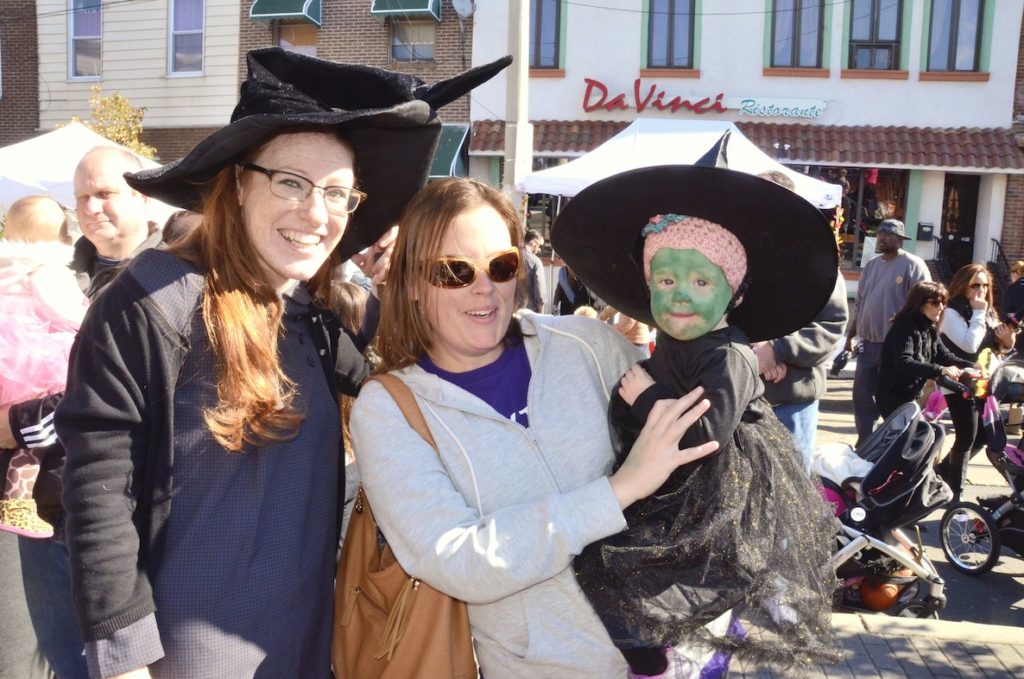 Two women post with their child, who's dressed like a witch, at the annual Fall Fest and Spooky Saturday event along East Passyunk Avenue in South Philly.