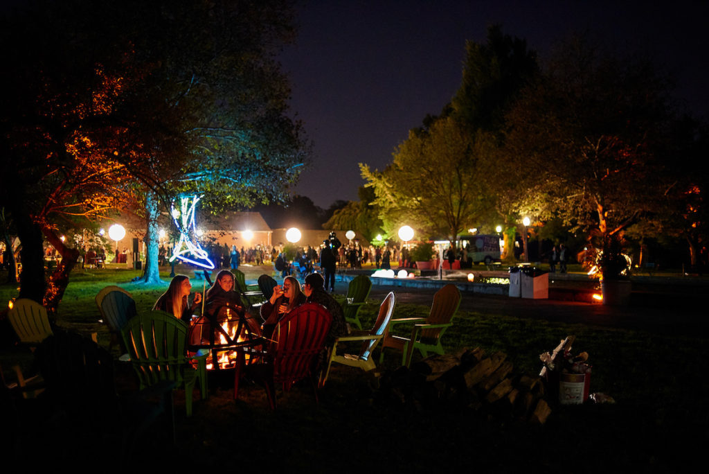 Guests gather around a fire pit at Glow in the Park, hosted by Fairmount Park Conservancy