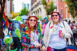 Two ladies dressed in head-to-toe rainbow gear smile for the camera at OutFest in Philadelphia