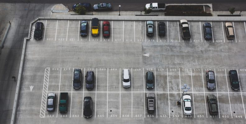 Cars park sporadically in a massive parking lot.