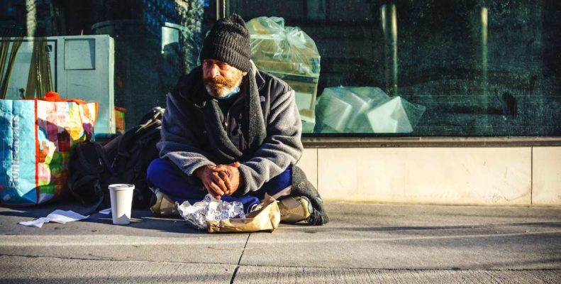 This photo of a homeless man sitting on the street accompanies a guide to how to help the homeless in Philadelphia