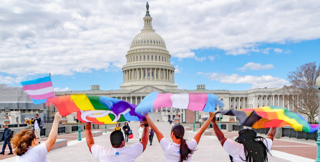 Youth raise transgender and rainbow flags in from the of the Capitol Building in Washington D.C.