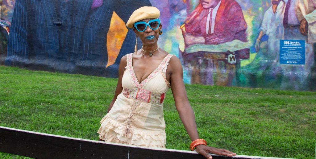 Aminata Sandra Calhoun poses in front of the Ed Bradley mural in West Philly's Belmont neighborhood.