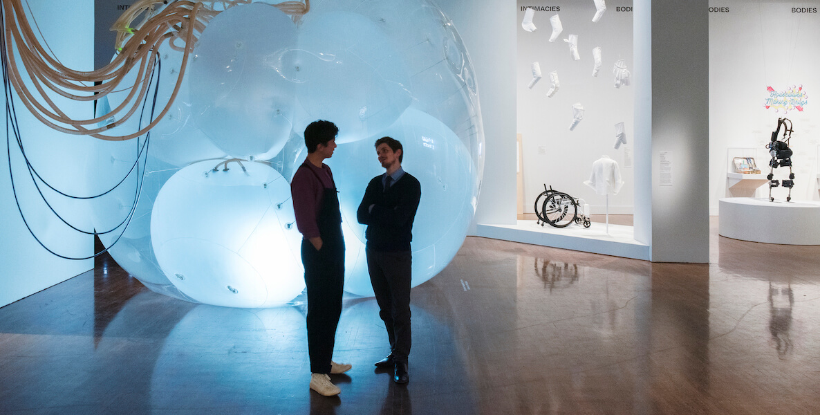 Two men stand chatting in the Philadelphia Museum of Art's Designs for Different Futures exhibition.