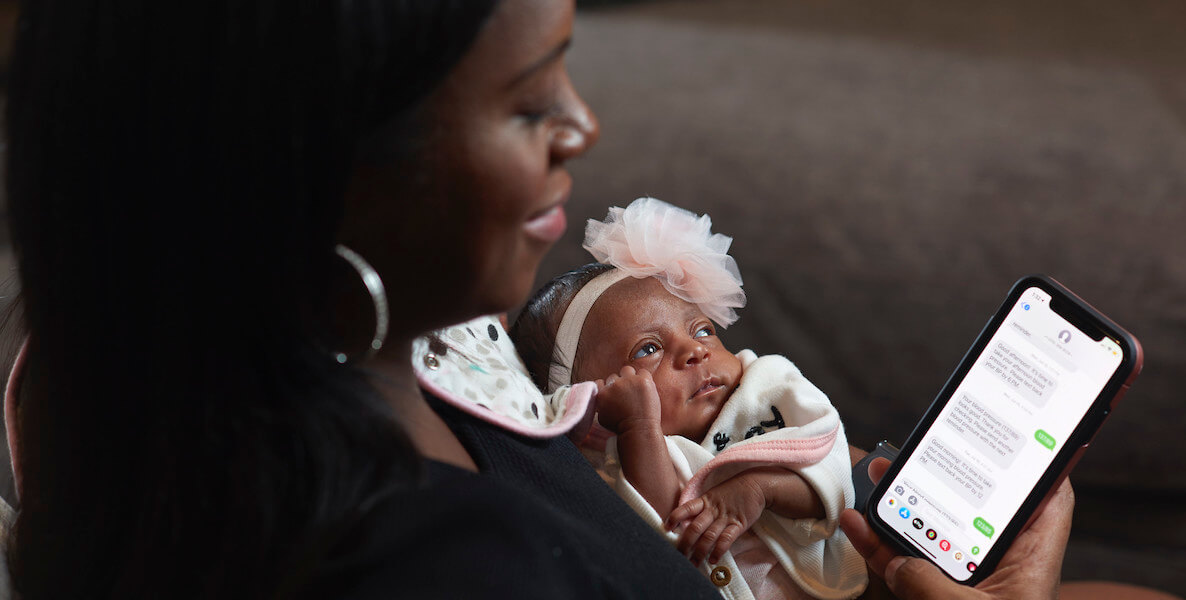 A mother holds her baby while engaging with the Heart Safe Motherhood technology created by Penn Medicine.