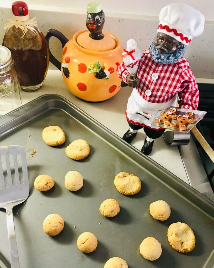Kitchen scene shows a baking sheet full of Kwanzaa cookies, with a black Santa standing to the right.