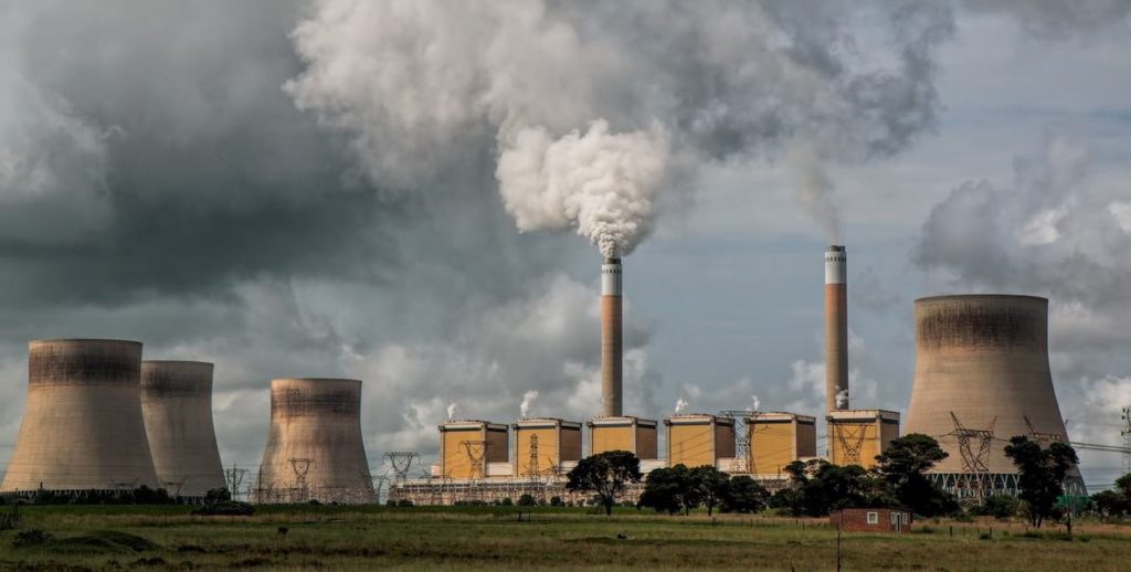 Smoke billows into the air from a factory smoke stack, releasing methane emissions into the atmosphere.