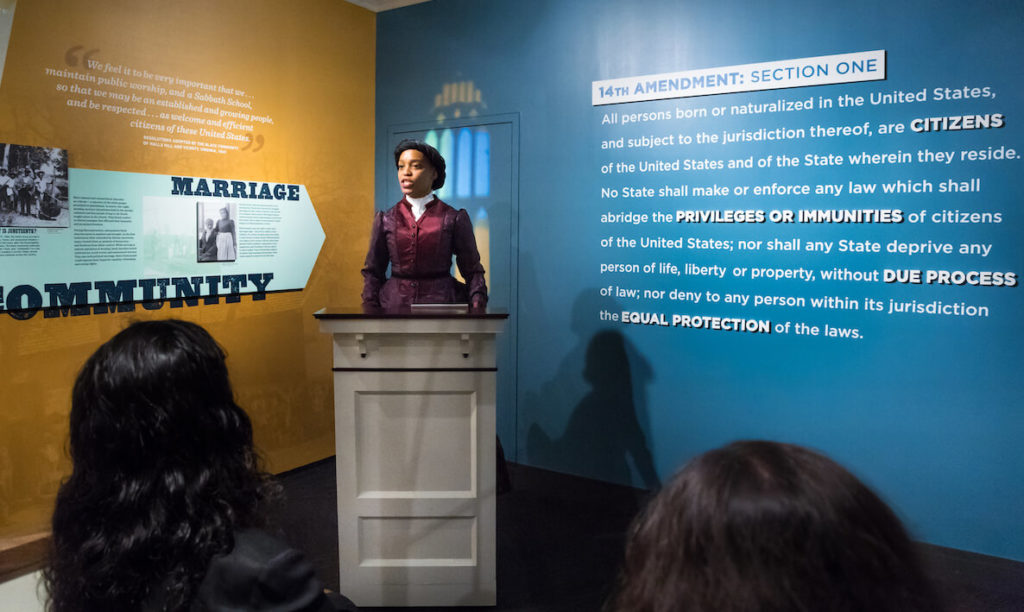 A woman dressed in 1880s period costume reads Martin Luther King's I Have a Dream Speech at the National Constitutional Center.