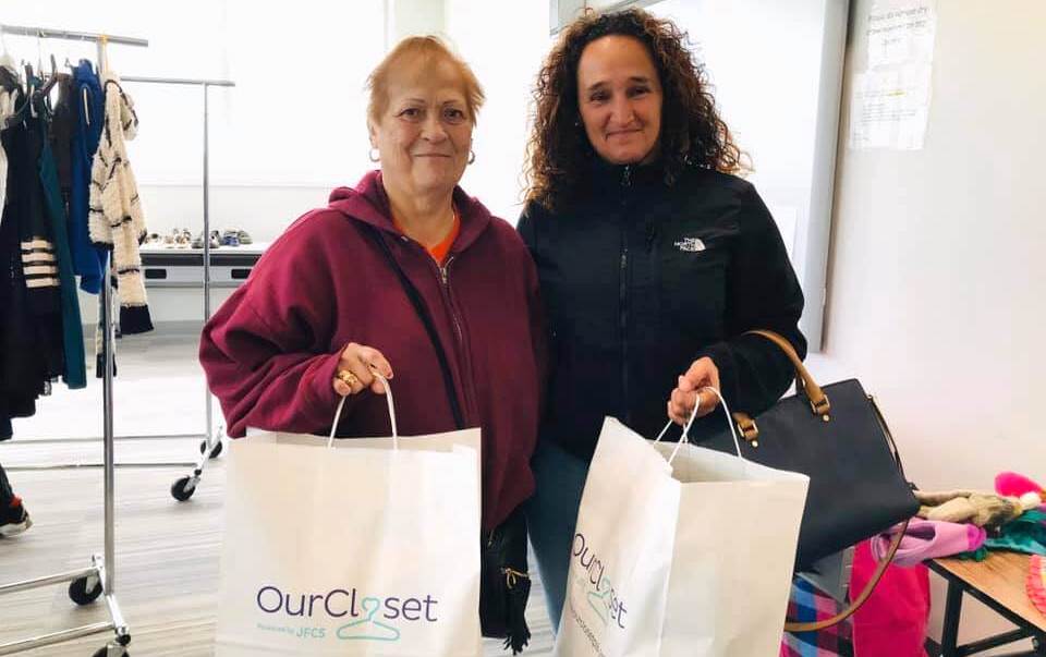 Two women hold up bags of clothing that they got from Our Closet in Philadelphia.