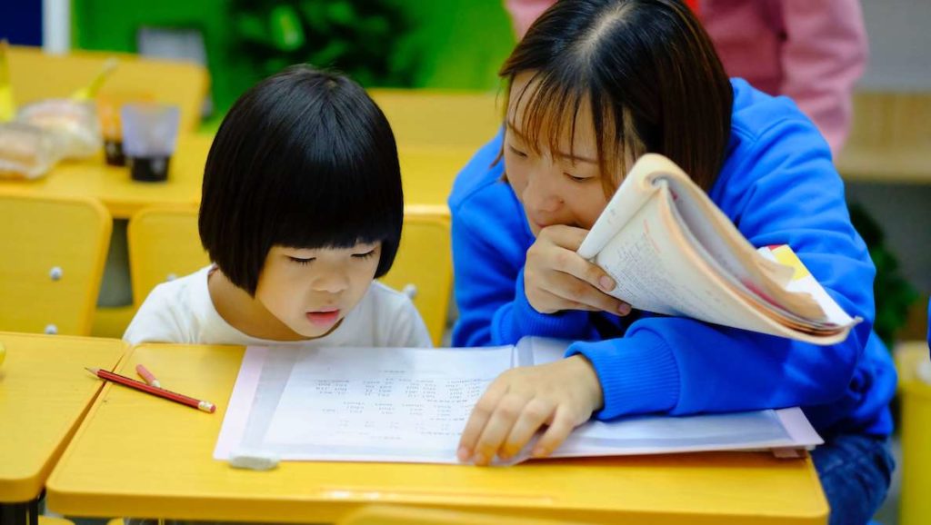 A woman teaches a young girl how to read. 