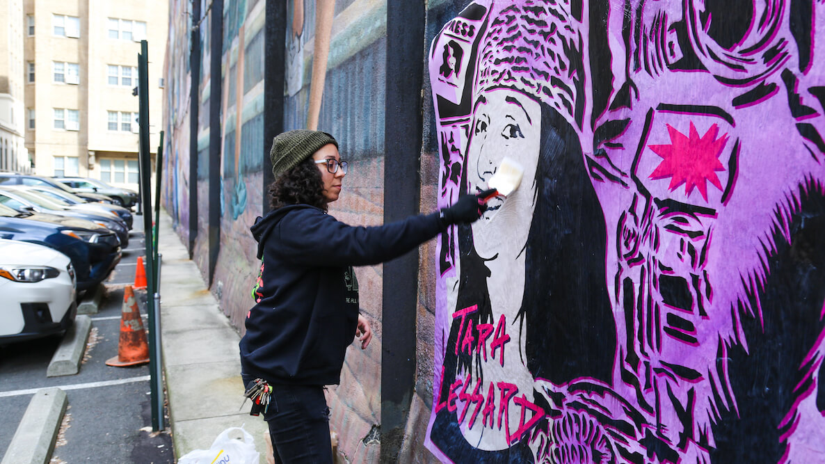 Nicole Krecicki/Taped Off TV puts up a mural of Tara Lessard, which is part of the #SisterLove street art project