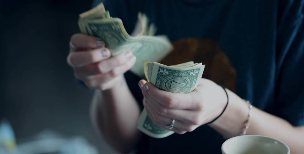 A woman counts her dollar bills after a successful stint of financial planning.