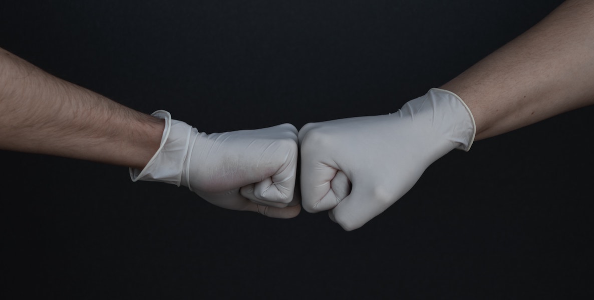 Two gloves do a fist bump during the coronavirus pandemic