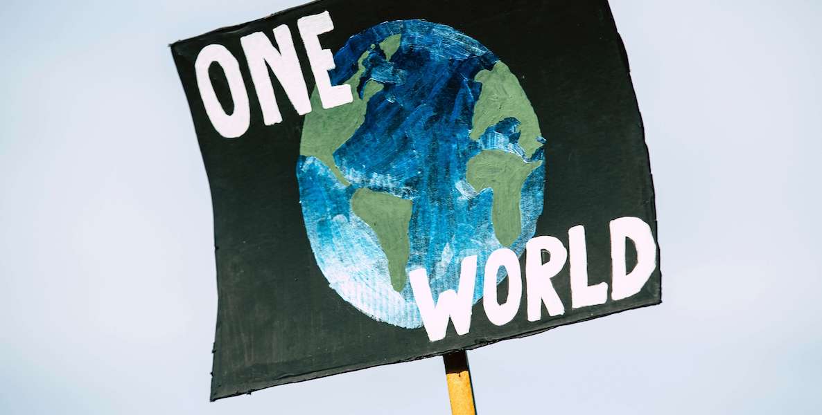 One side of a shovel is painted with a picture of the planet and words that say, "One World."