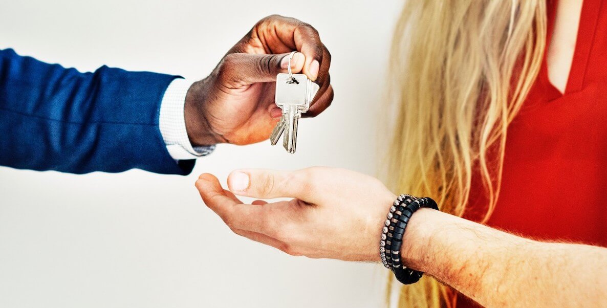 A landlord hands over keys to two renters.