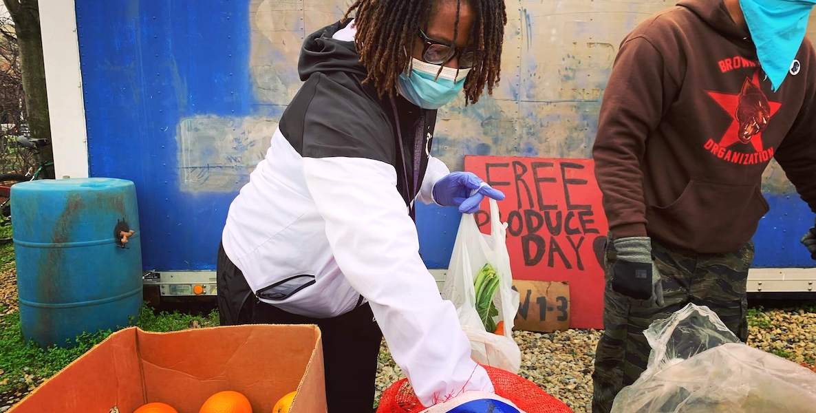 A woman loads up a bag with oranges at North Philly Peace Park to help feed families in need during the coronavirus pandemic.