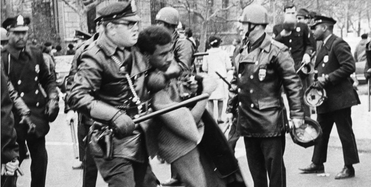 In 1967, a cop has a Black man in a chokehold during a march to protest inadequate schooling for Black Philadelphians.